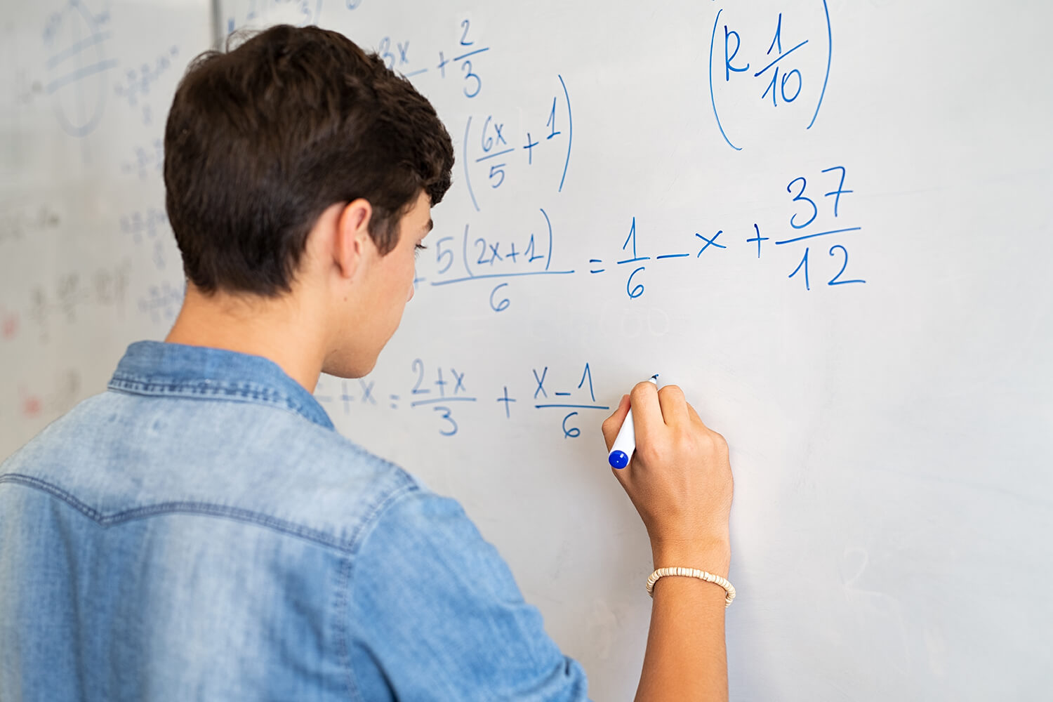 A young man solving a math problem on white board