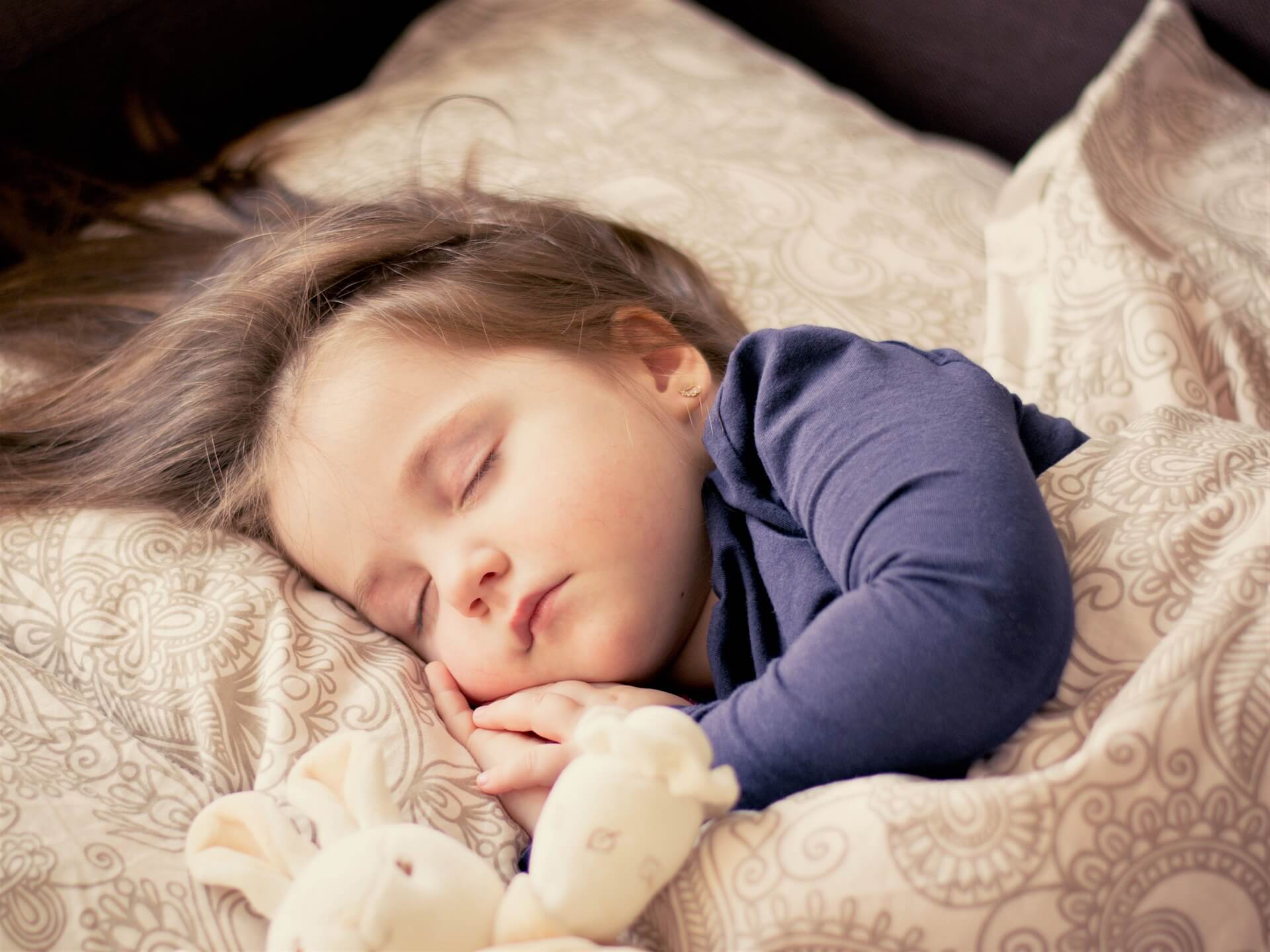 A toddler sleeping next to a plush bunny